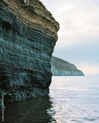 Rugged coastal cliffs with layered textures and calm ocean view, showcasing dramatic natural beauty for wall art photo