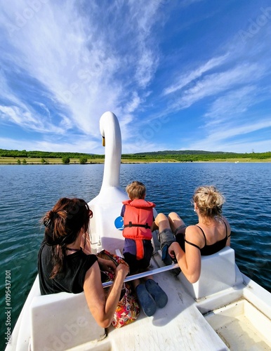 Two women and a boy ride a swan-shaped pedal boat. Milada Lake, Czech Republic, Europe. photo