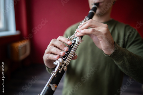 Clarinet player. Clarinetist hands playing flute woodwind music instrument closeup at home, soft focus. Musical instruments. Guy plays the oboe in education classroom. Hobby. 