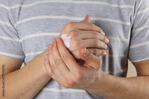 Man applying moisturizing cream onto hand, closeup