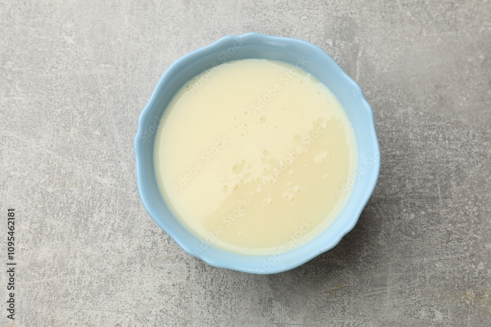 Condensed milk in bowl on light grey table, top view Condensed milk in bowl on light grey table, top view
