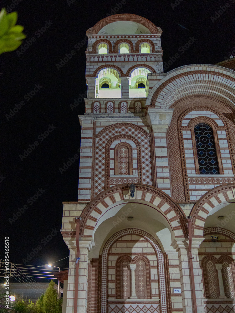 Obraz premium A stunning church with intricate brickwork and colorful designs stands tall against the night sky. Illuminated windows highlight its historical significance and craftsmanship.