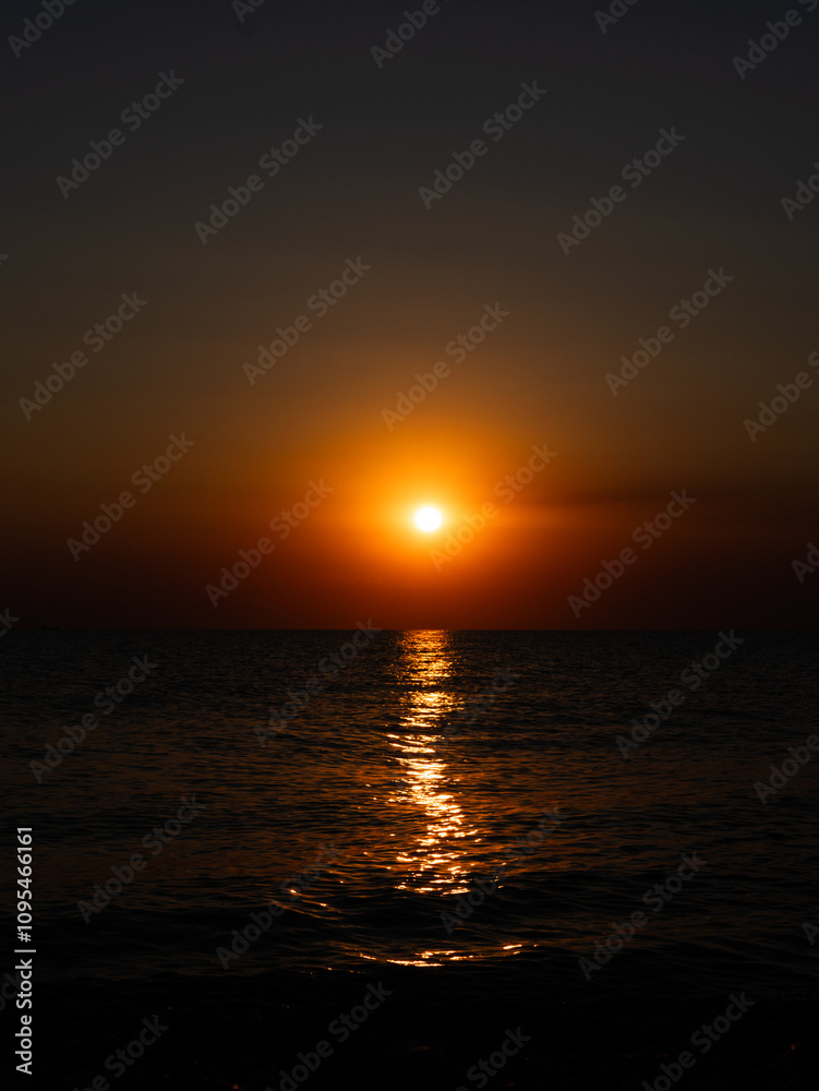 A stunning sunset paints the sky orange and gold as the sun descends beyond the horizon, casting shimmering reflections on the calm ocean water during early evening. A stunning sunset paints the sky orange and gold as the sun descends beyond the horizon, casting shimmering reflections on the calm ocean water during early evening.