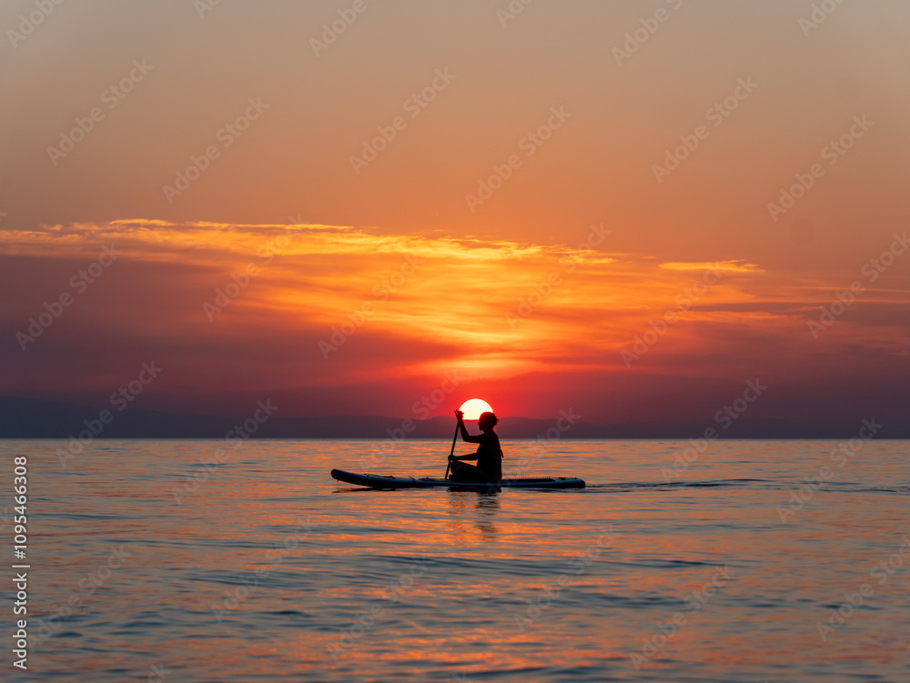 A paddler navigates through tranquil waters during sunset, surrounded by vibrant hues of orange and purple in the sky, creating a peaceful atmosphere. A paddler navigates through tranquil waters during sunset, surrounded by vibrant hues of orange and purple in the sky, creating a peaceful atmosphere.