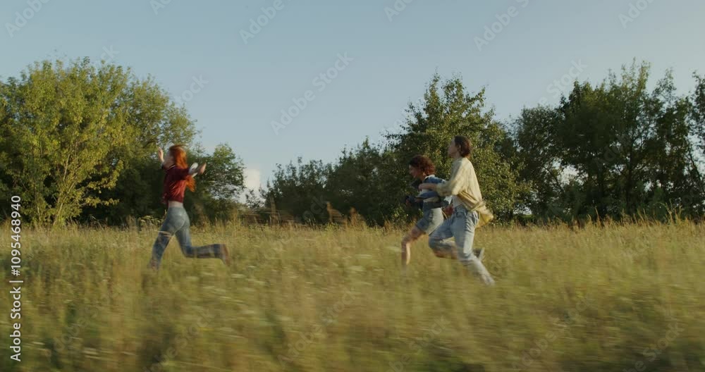 Three young friends are having fun and running around the field on a sunny summer day. Holidays in the countryside Three young friends are having fun and running around the field on a sunny summer day. Holidays in the countryside