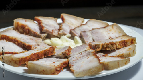 Slices of boiled pork meat with pepper served with garlic in a vibrant culinary display