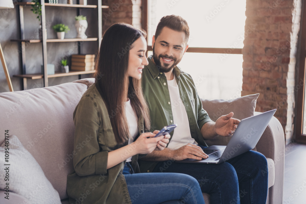 Photo of positive cute married people wife husband sit on couch distance shopping loft interior apartment indoors Photo of positive cute married people wife husband sit on couch distance shopping loft interior apartment indoors