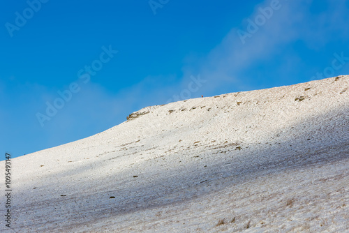 Lone hiker on the summit of a snow covered Corn Du in the Brecon Beacons, Wales