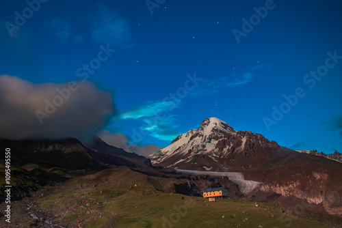 Breathtaking night sky filled with stars illuminates a snowy mountain peak Kazbek (Kazbegi) Caucasus