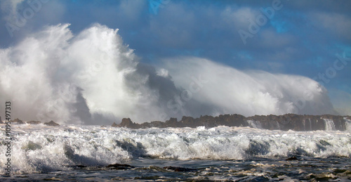 Ocean wave crashing over rocky island patch