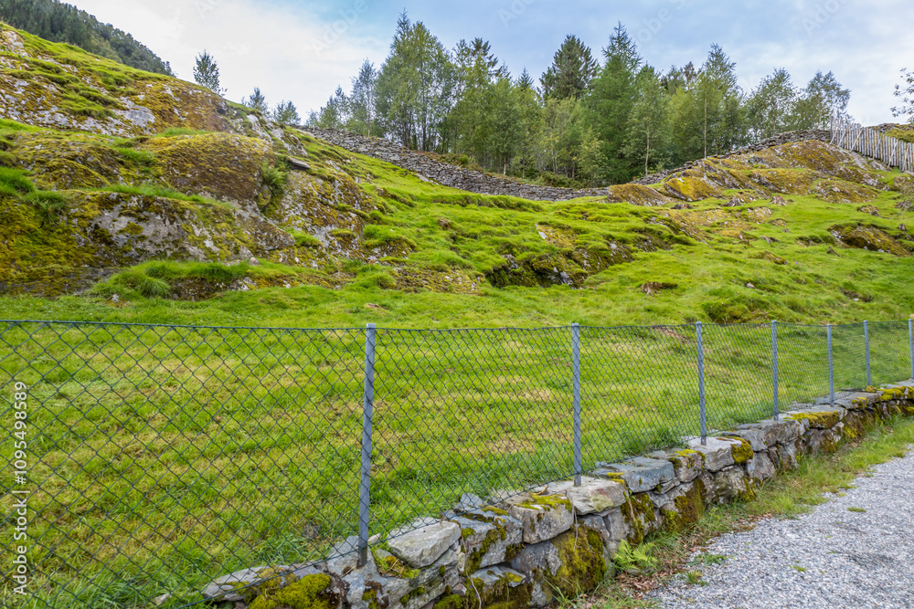 Full frame landscape texture background of a fenced Norwegian pasture with rocky hillside terrain Full frame landscape texture background of a fenced Norwegian pasture with rocky hillside terrain