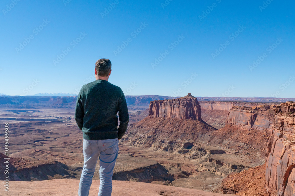 Man overlooking vast expanses of canyons, mesas and buttes in canyonlands national park, towards the snowcapped mountains of the La Sal range, Utah, USA. Man overlooking vast expanses of canyons, mesas and buttes in canyonlands national park, towards the snowcapped mountains of the La Sal range, Utah, USA.