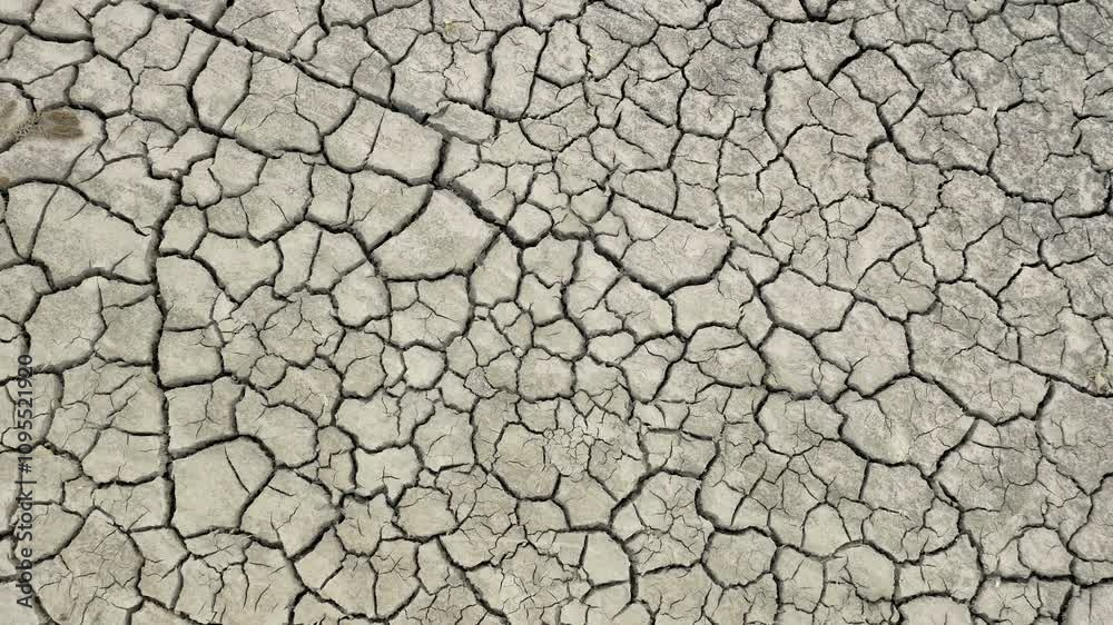 Desolate landscape with severely cracked soil, reflecting the harshness of the drought. The ground is dry and broken, with no signs of life or water, highlighting the environmental crisis