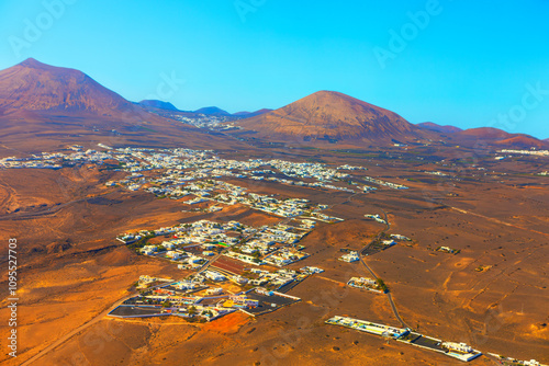 Guatiza village on Lanzarote is nestled in a vast, arid landscape characterized by sparse vegetation and volcanic terrain. Barren land of Canary Islands is surrounded by  prominent volcanic hills photo