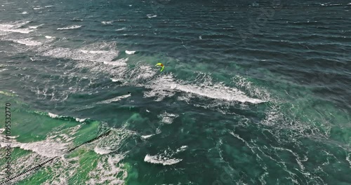 Outstanding kitesurfer riding on big waves at Baltic Sea.