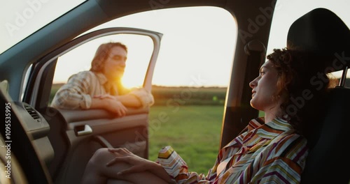 Wallpaper Mural A woman is sitting in a car, a man is standing near the open door, they are smiling and talking. A sunset date in a field Torontodigital.ca