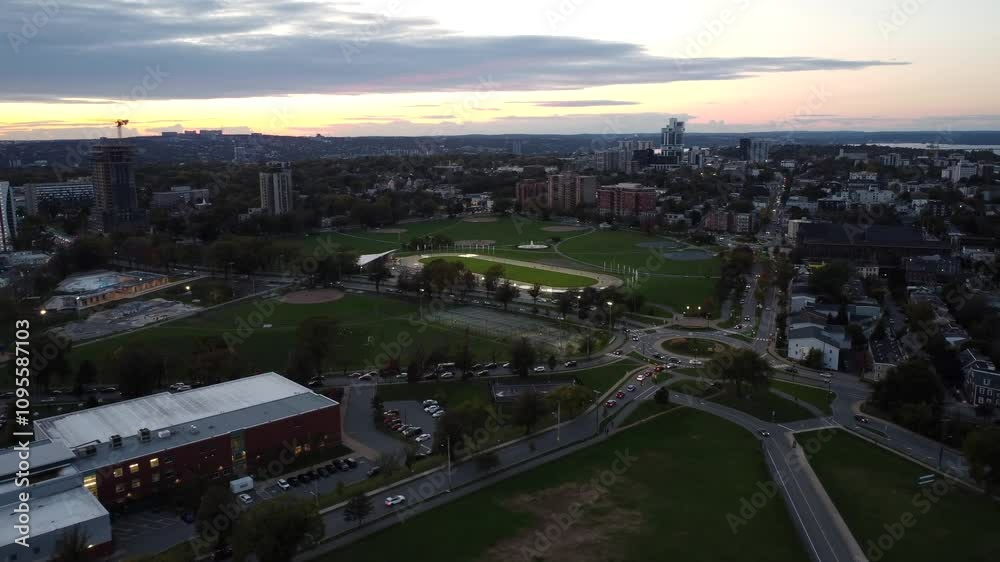Drone flies over city park with baseball diamonds and tennis courts. Evening American and Canadian city. City of Halifax, road with cars. Flight over the city.