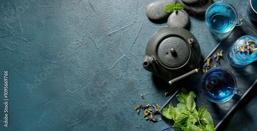 Glass cups of organic blue tea, dried flowers and mint on dark background photo