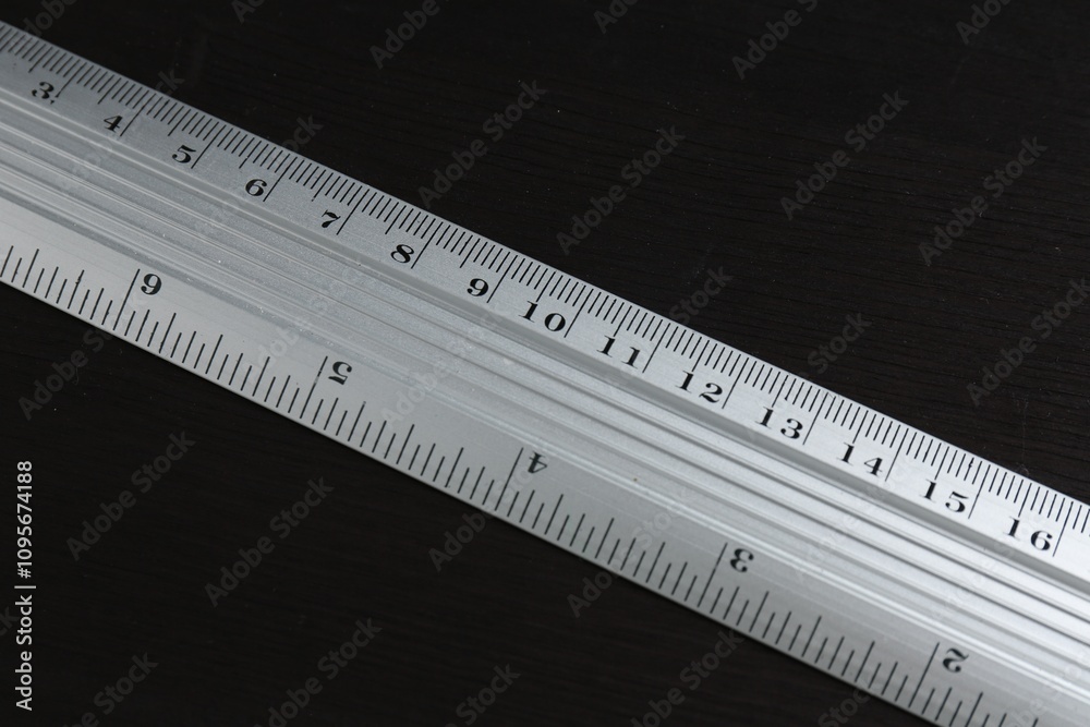 One metal ruler on black wooden table, above view One metal ruler on black wooden table, above view