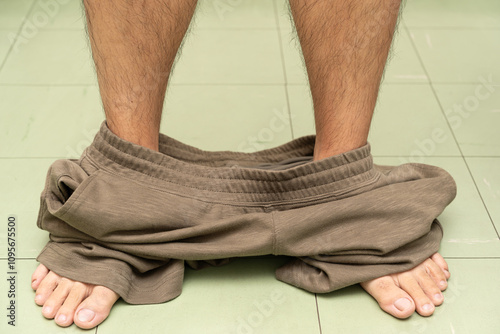 man taking off his shorts or pants on the floor.  photo