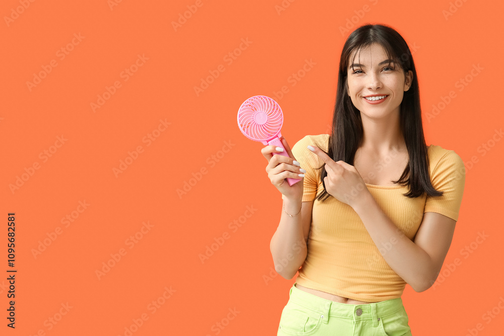 Young woman with mini fan on orange background Young woman with mini fan on orange background