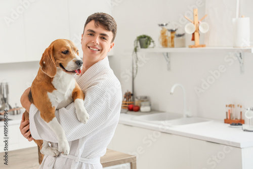 Young man in bathrobe holdi...