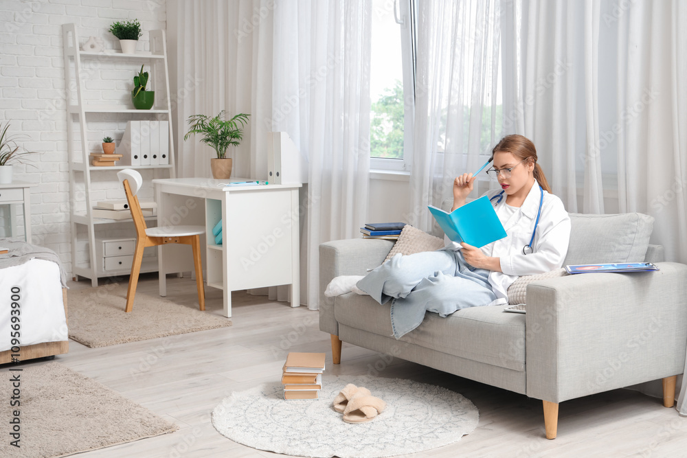 Female medical student studying with notebook on sofa at home Female medical student studying with notebook on sofa at home