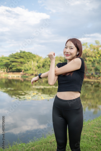 A woman is stretching her arms in front of a lake