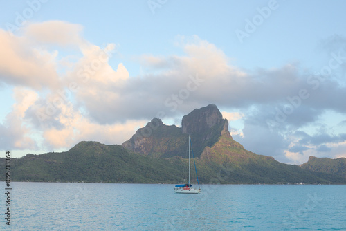 A view of a sailing boat in lagoon, mountain and clouds