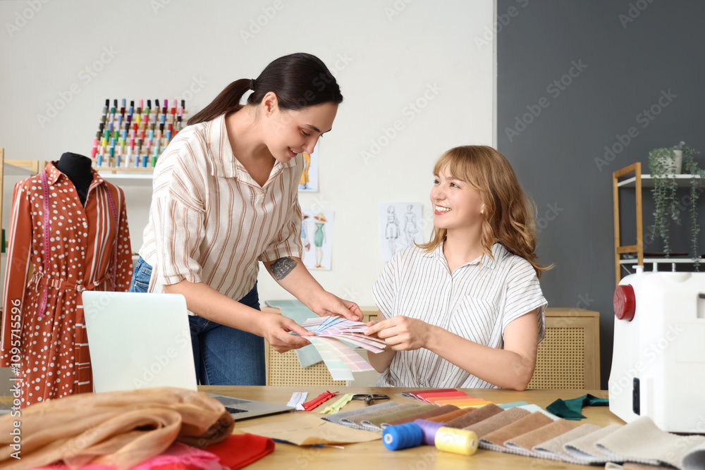 Fototapeta premium Female tailors working with color palettes at table in atelier
