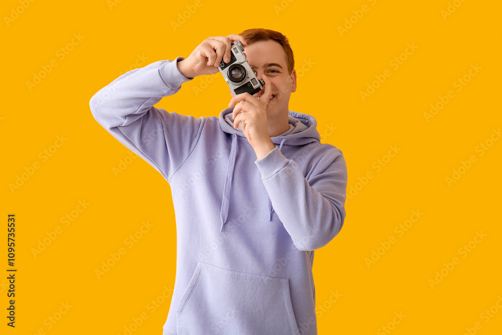 Young man with photo camera on yellow background Young man with photo camera on yellow background