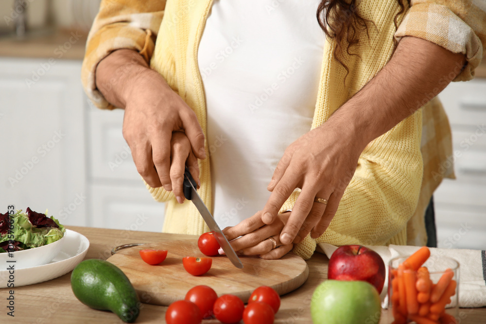 Married couple cutting tomato in kitchen, closeup Married couple cutting tomato in kitchen, closeup