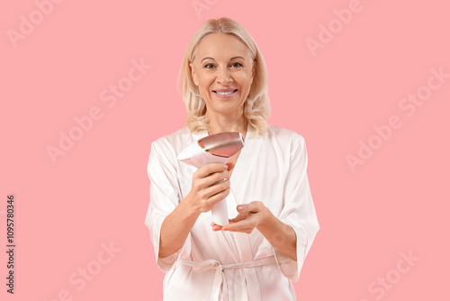 Mature woman with photoepilator on pink background photo