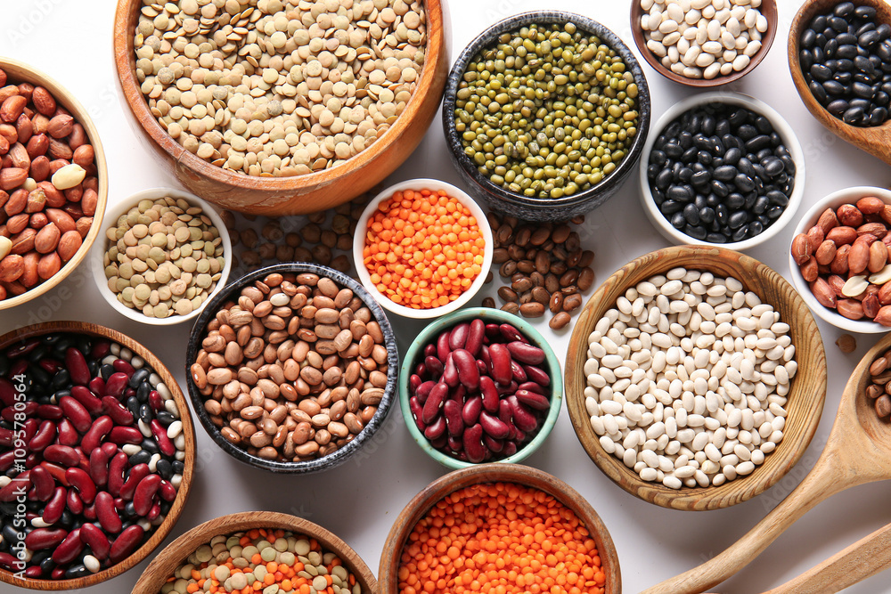Composition with bowls of different raw legumes on white background Composition with bowls of different raw legumes on white background