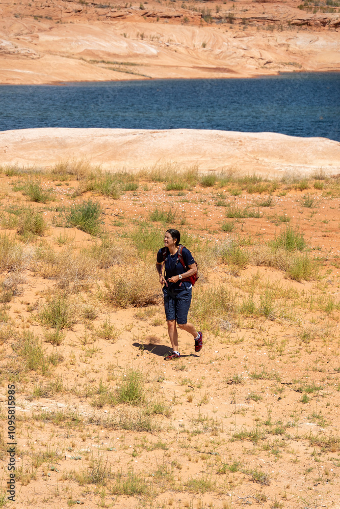 Man walking through arid landscape near a lake during sunny day in summer Man walking through arid landscape near a lake during sunny day in summer
