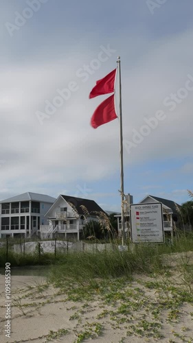 Double red flags indicating closed waters next to informational signs tucked in sand dunes with sea oats on Cape San Blas in the Florida panhandle. photo