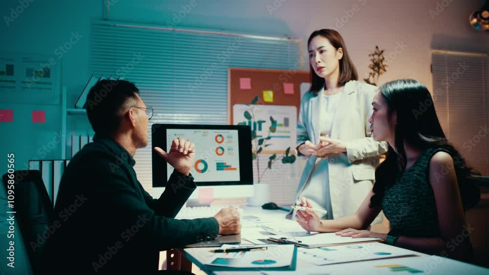Business people working late at night in the office. A marketing team analyzes data and discusses sales using charts on a computer screen Business people working late at night in the office. A marketing team analyzes data and discusses sales using charts on a computer screen