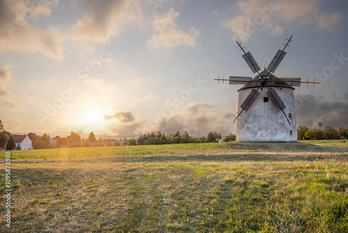 Windmill with wooden wings in a landscape setting. Fields, meadows and flowers appear in the sunset. Landscape shot in nature with a mill. historically untypical for the Balaton region in Hungary