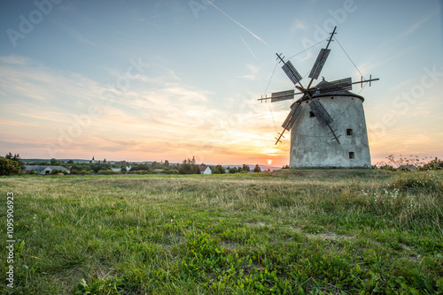 Windmill with wooden wings in a landscape setting. Fields, meadows and flowers appear in the sunset. Landscape shot in nature with a mill. historically untypical for the Balaton region in Hungary