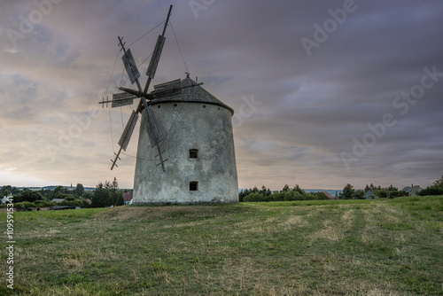 Windmill with wooden wings in a landscape setting. Fields, meadows and flowers appear in the sunset. Landscape shot in nature with a mill. historically untypical for the Balaton region in Hungary photo