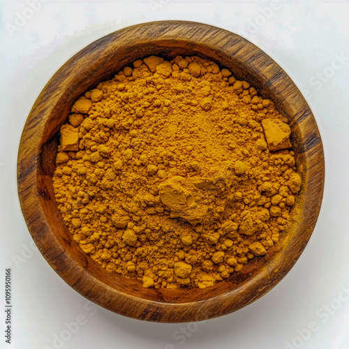 A wooden bowl of termeric powder against a white background photo