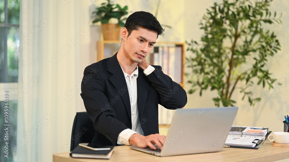 Exhausted businessman experiencing neck and shoulder pain from long hours at working desk Exhausted businessman experiencing neck and shoulder pain from long hours at working desk