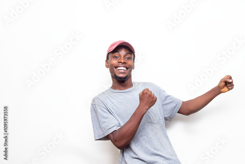 A cheerful young man wearing a gray shirt and pink cap, isolated over a white background expressing happiness and success. His joyful pose and bright smile convey a sense of optimism ,positive energy.