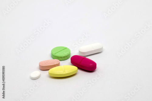 A variety of colorful tablets and pills are scattered on a white surface, representing diversity in medication and healthcare options.