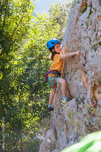 rock climber boy. child is practicing rock climbing. summer camp. sport in nature. cute teenager climbing on a rock with belay photo