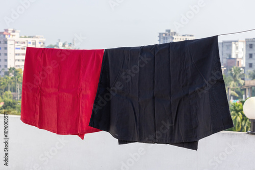 A red and black petticoat hanging on clothesline on rooftop, drying in the sun. Petticoats are traditional undergarments worn by women with sarees or other traditional clothing.