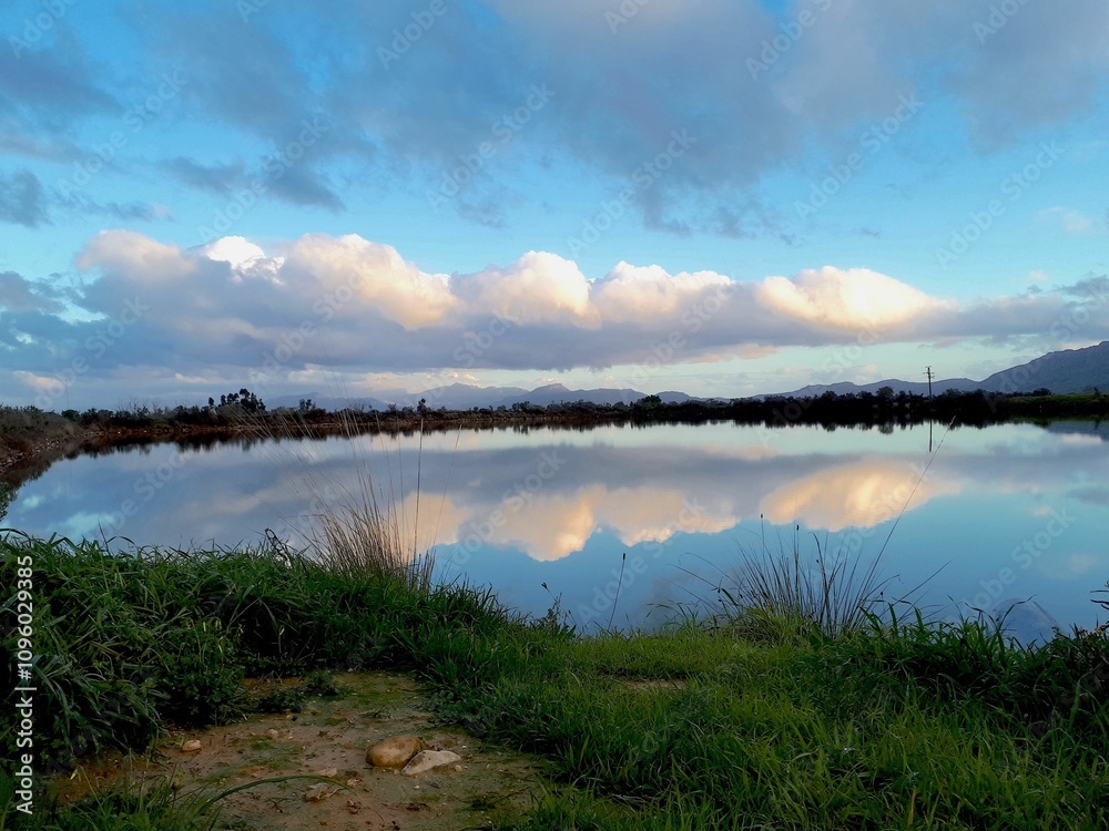 Serene lake landscape with cloud reflections.