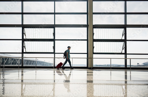 Canvas Print Man walking with suitcase at airport terminal.