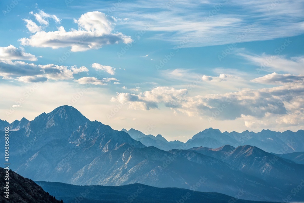 Soft blue sky with a few wispy clouds peeking over the top of a rugged mountain range, natural beauty, sky Soft blue sky with a few wispy clouds peeking over the top of a rugged mountain range, natural beauty, sky