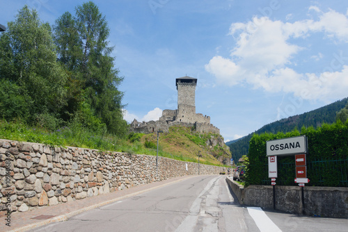 The entrance road to the Alpine village of Ossana. In the background the Castle of San Michele (Italian: Castello di San Michele). Trentino-Alto-Adige, Italy